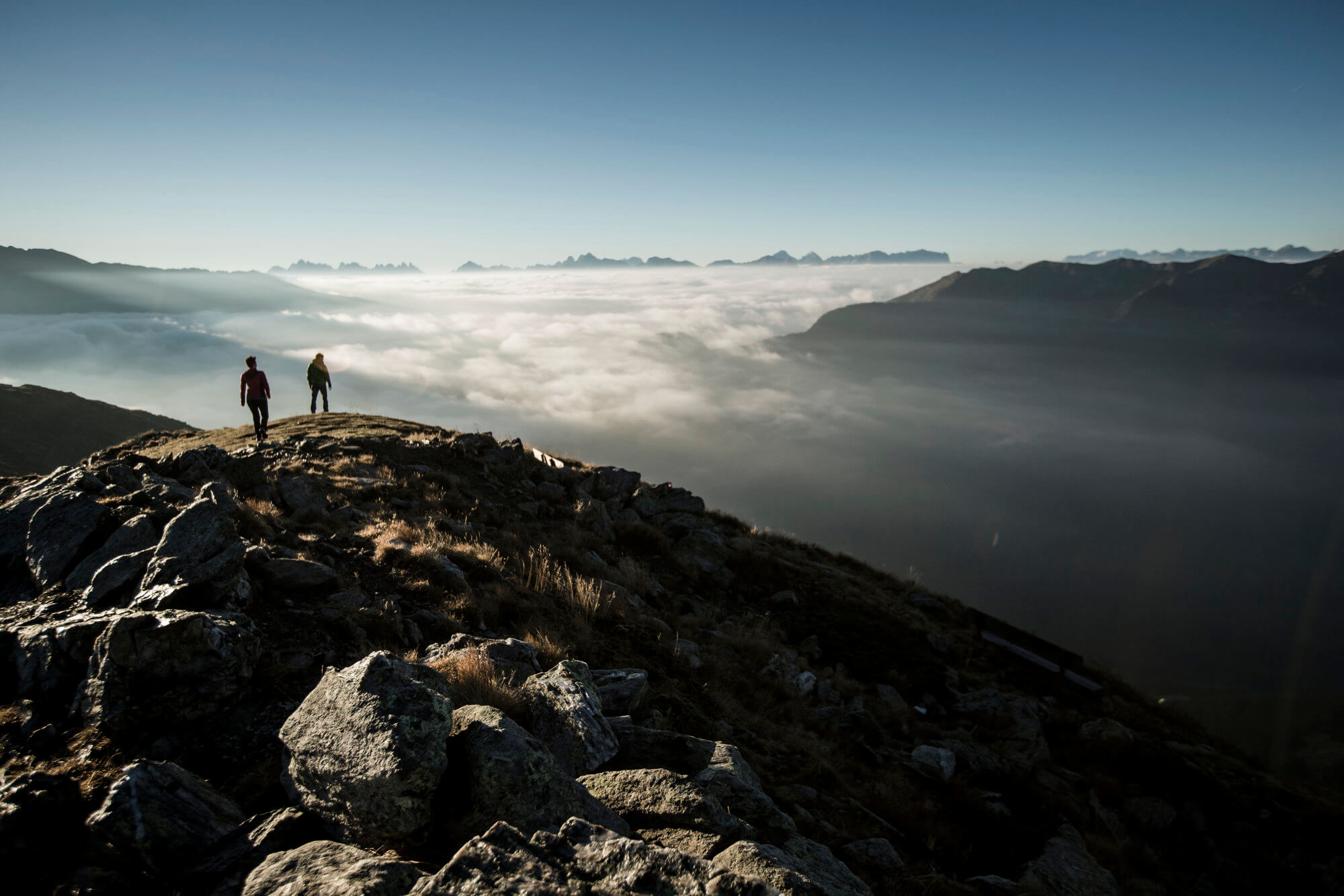 Blick vom Berggipfel auf das Tal, welches von Nebel überzogen ist - AHRIA Apartments