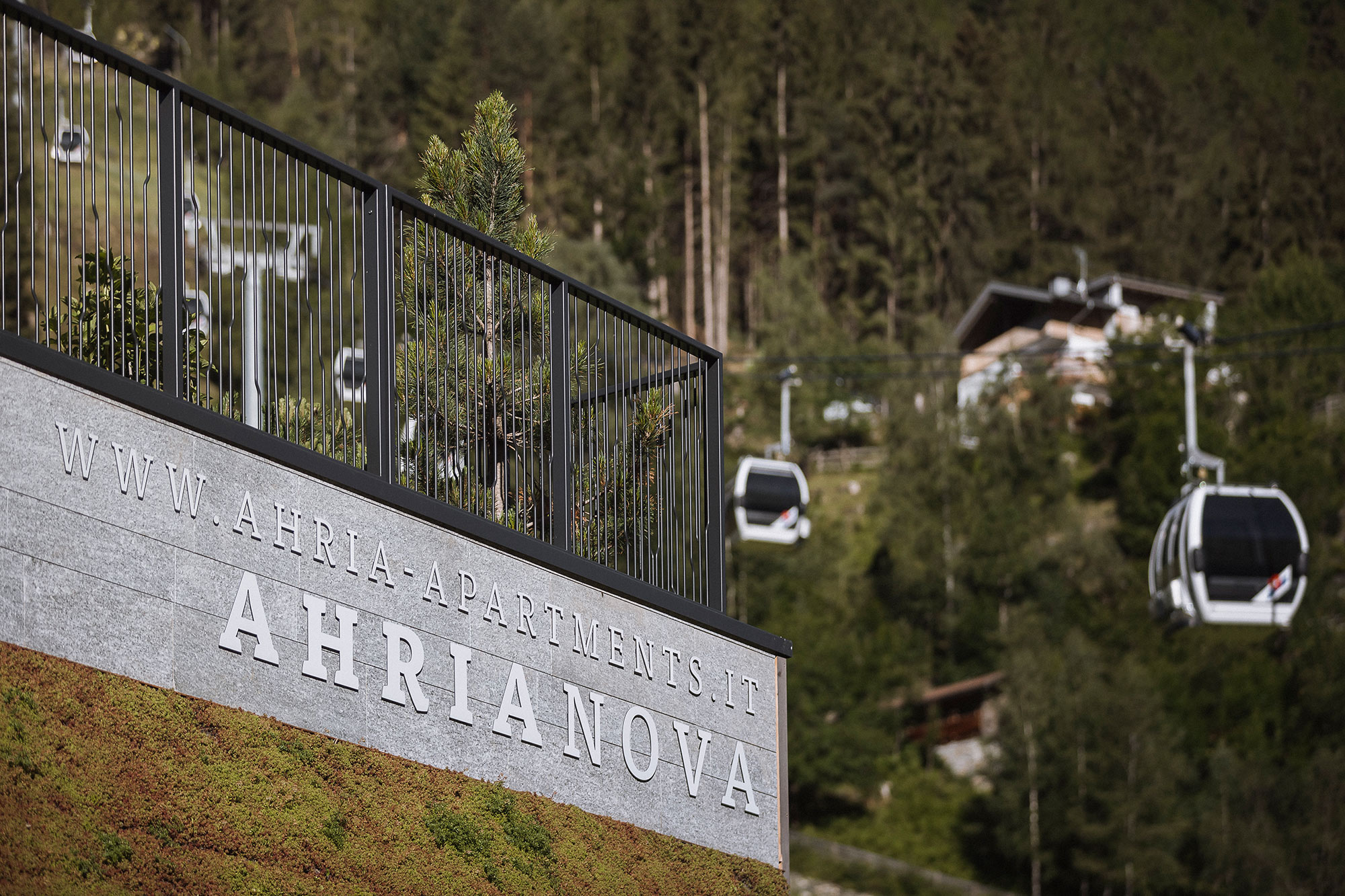 AhriaNova Logo an der Fassade mit der Bergbahn im Hintergrund - AHRIA Apartments
