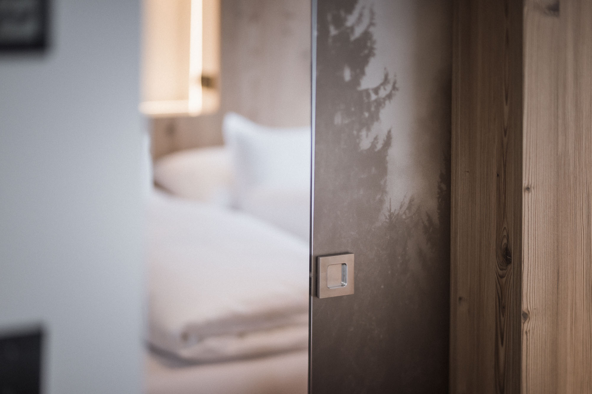 Schiebetür mit Walddesign um ins Schlafzimmer zu gelangen im Apartment AhriaNova - AHRIA Apartments