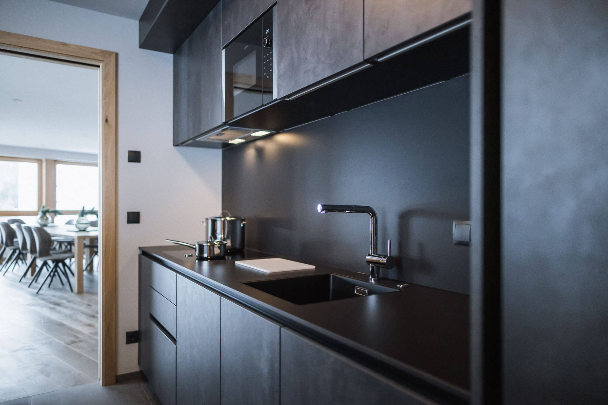 Küchenzeile im dunklen Design Richtung Wohnbereich vom Apartment AhriaNova - AHRIA Apartments