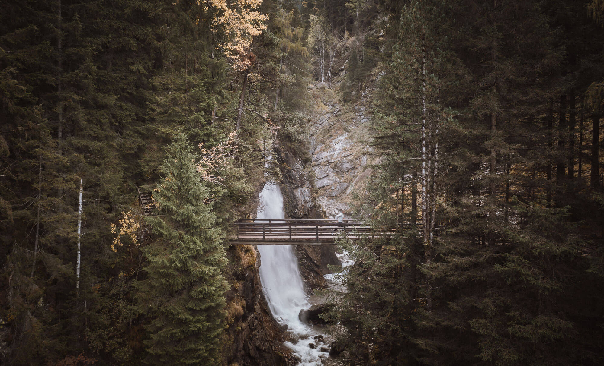 Mann läuft über die Brücke bei den Reinbacher Wasserfällen - AHRIA Apartments