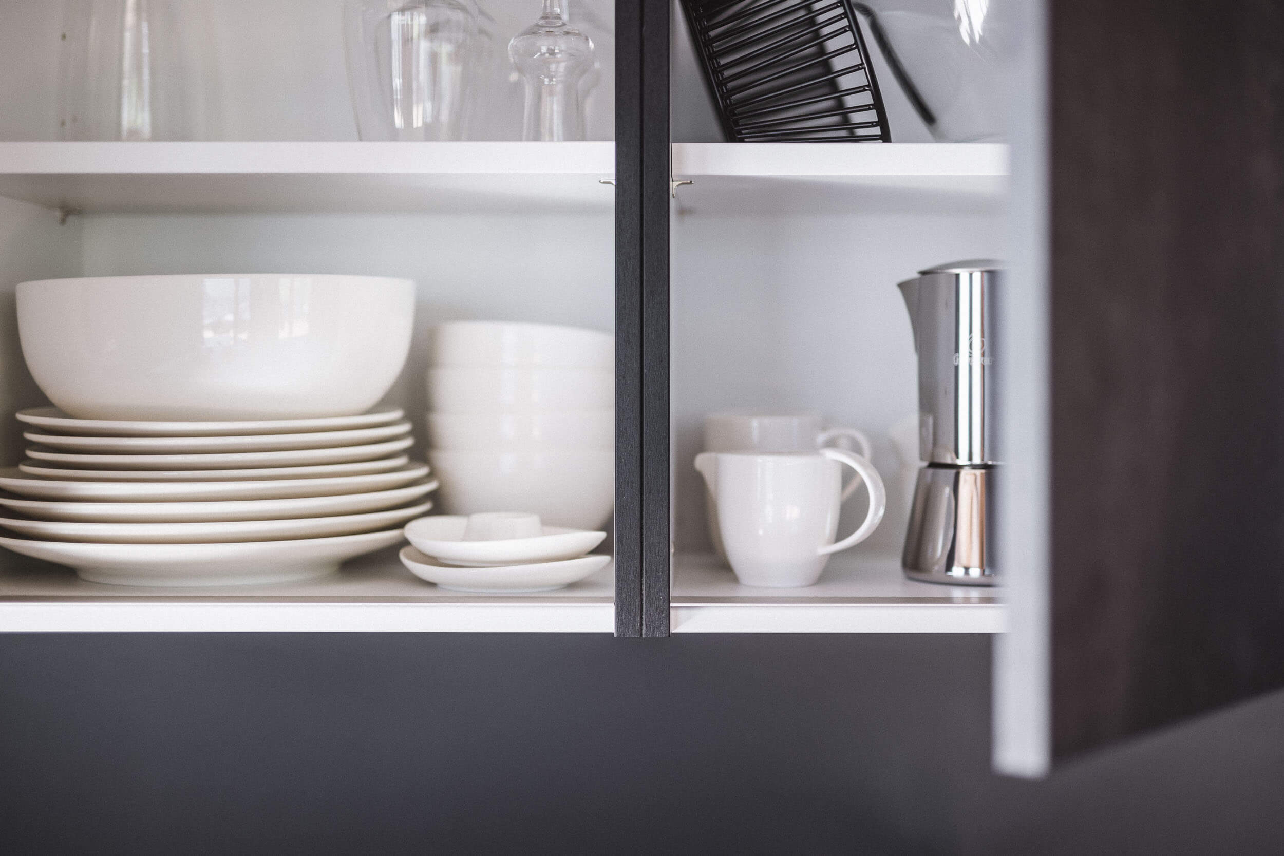 Hochschränke mit Geschirr in der Küche vom AhriaPura Apartment - AHRIA Apartments