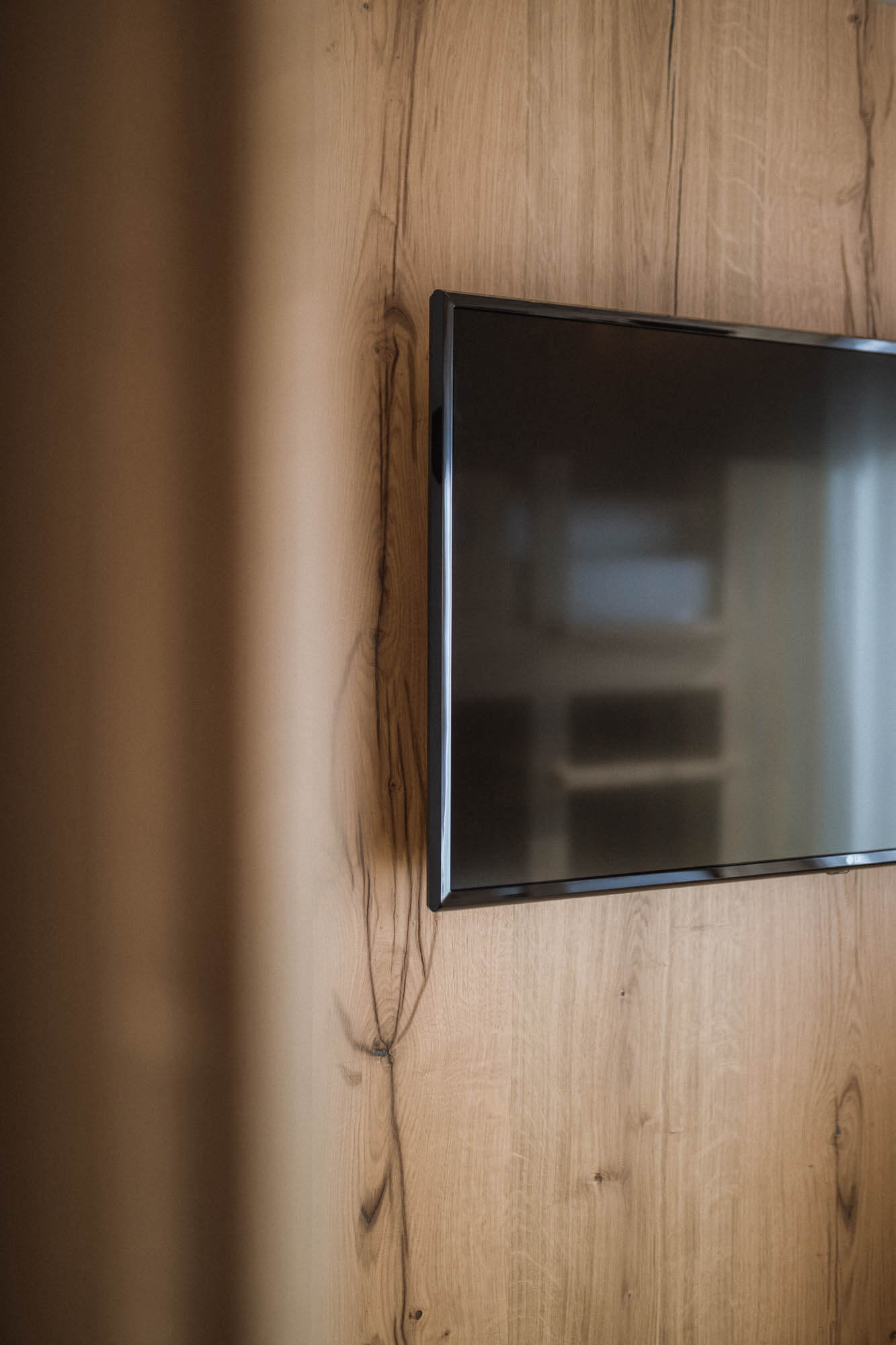 Fernseher auf einer Holzwand im AhriaPura Apartment - AHRIA Apartments
