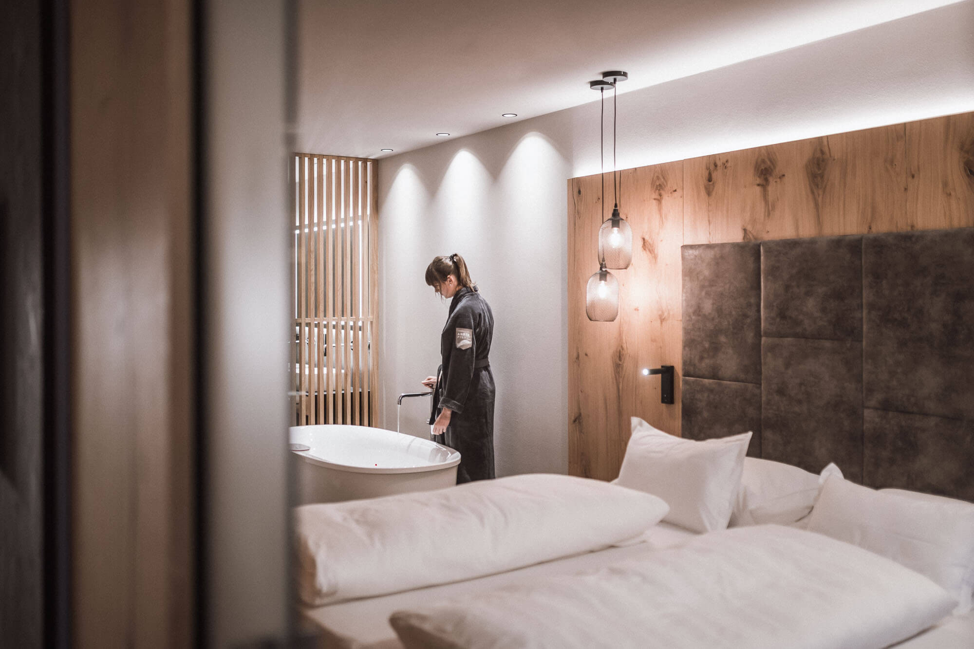 Frau lässt sich ein Bad in der freistehenden Badewanne im AhriaPura Apartment ein - AHRIA Apartments