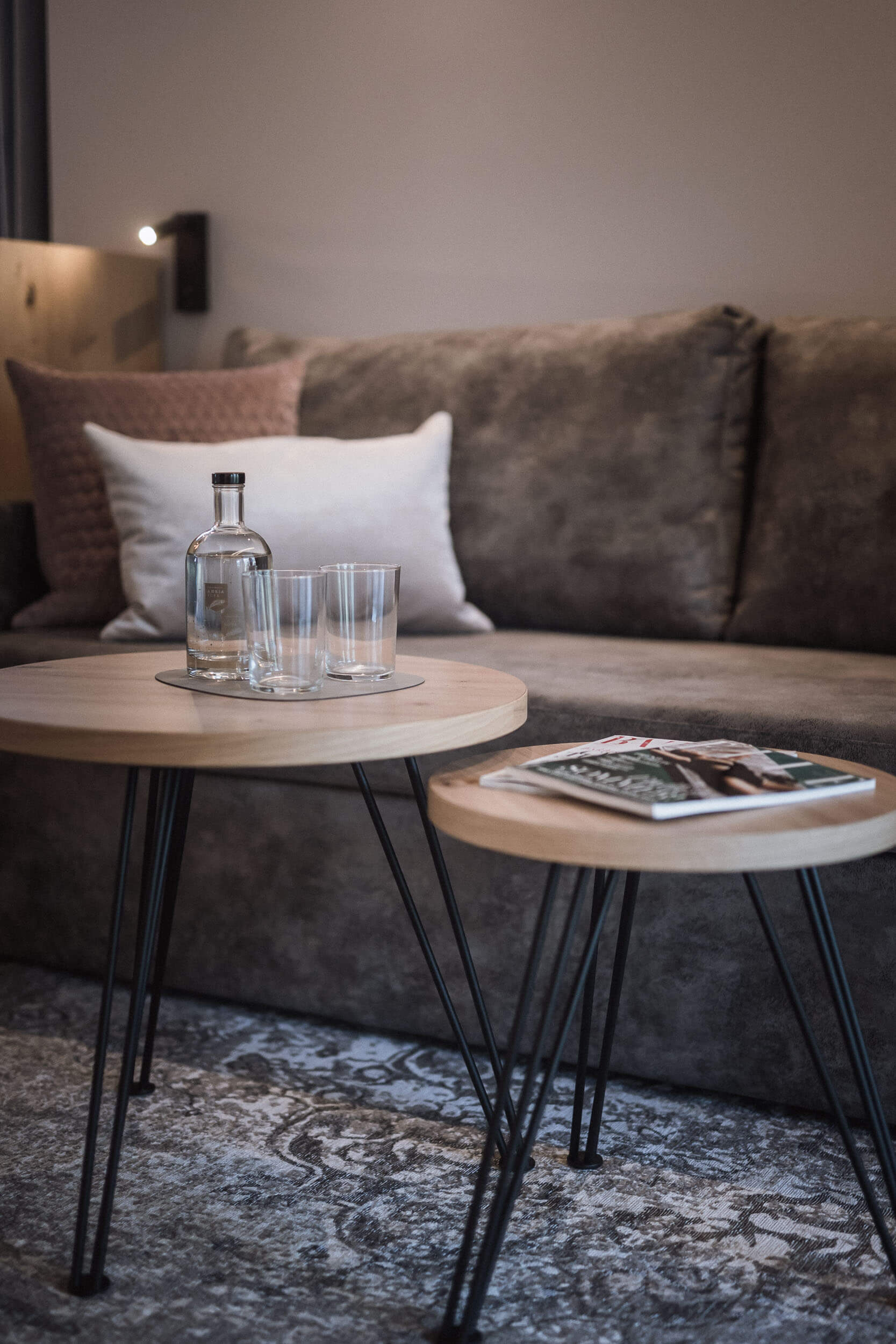 Couchtische aus Holz und Metall vor einem grauen Sofa im AhriaPura Apartment - AHRIA Apartments