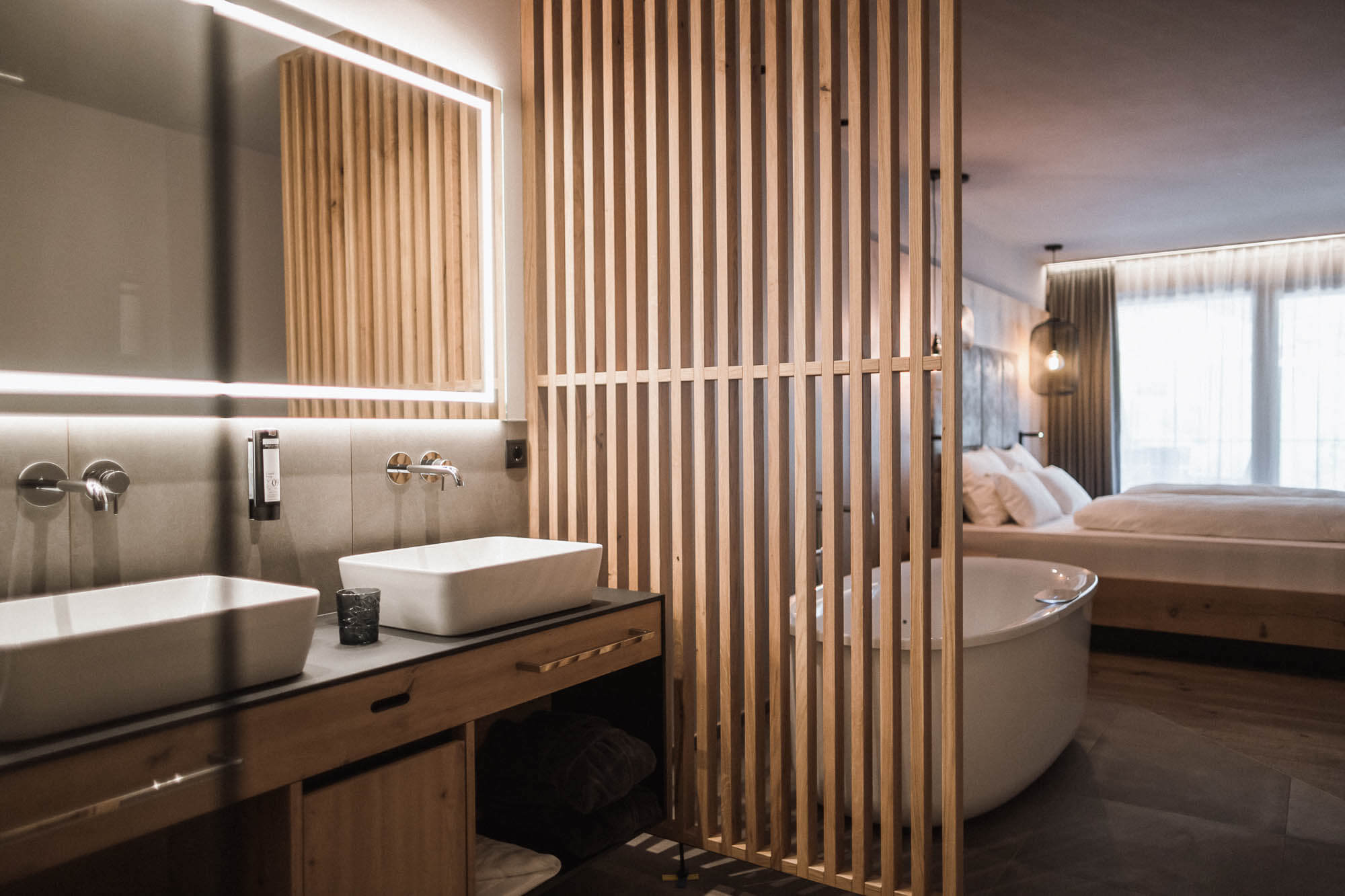 Holzabtrennung zwischen Badezimmer und freistehender Badewanne im Schlafzimmer im AhriaPura Apartment - AHRIA Apartments