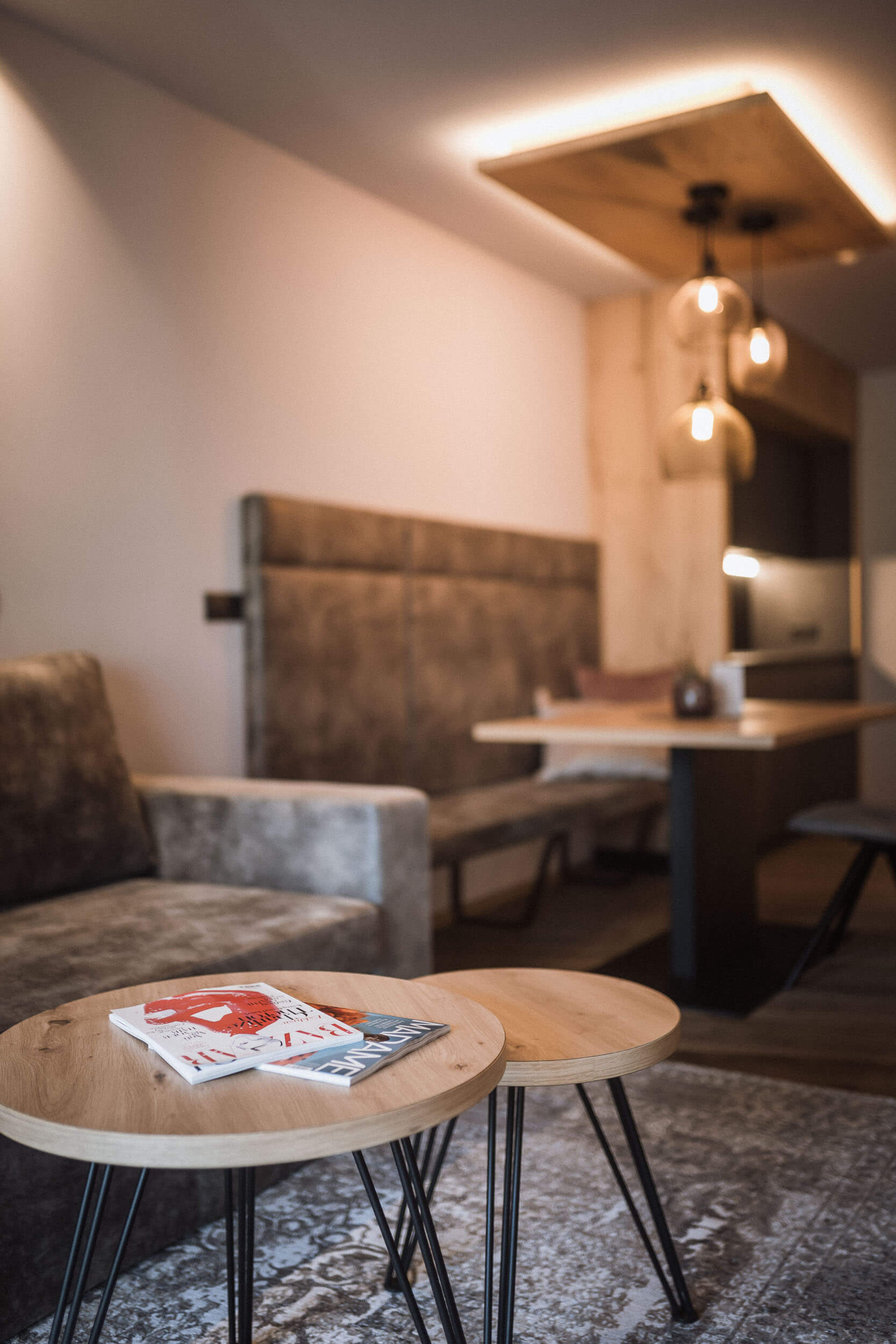 Couchtische mit Magazine und ein Tisch mit Bank und Stühlen im Hintergrund - AHRIA Apartments