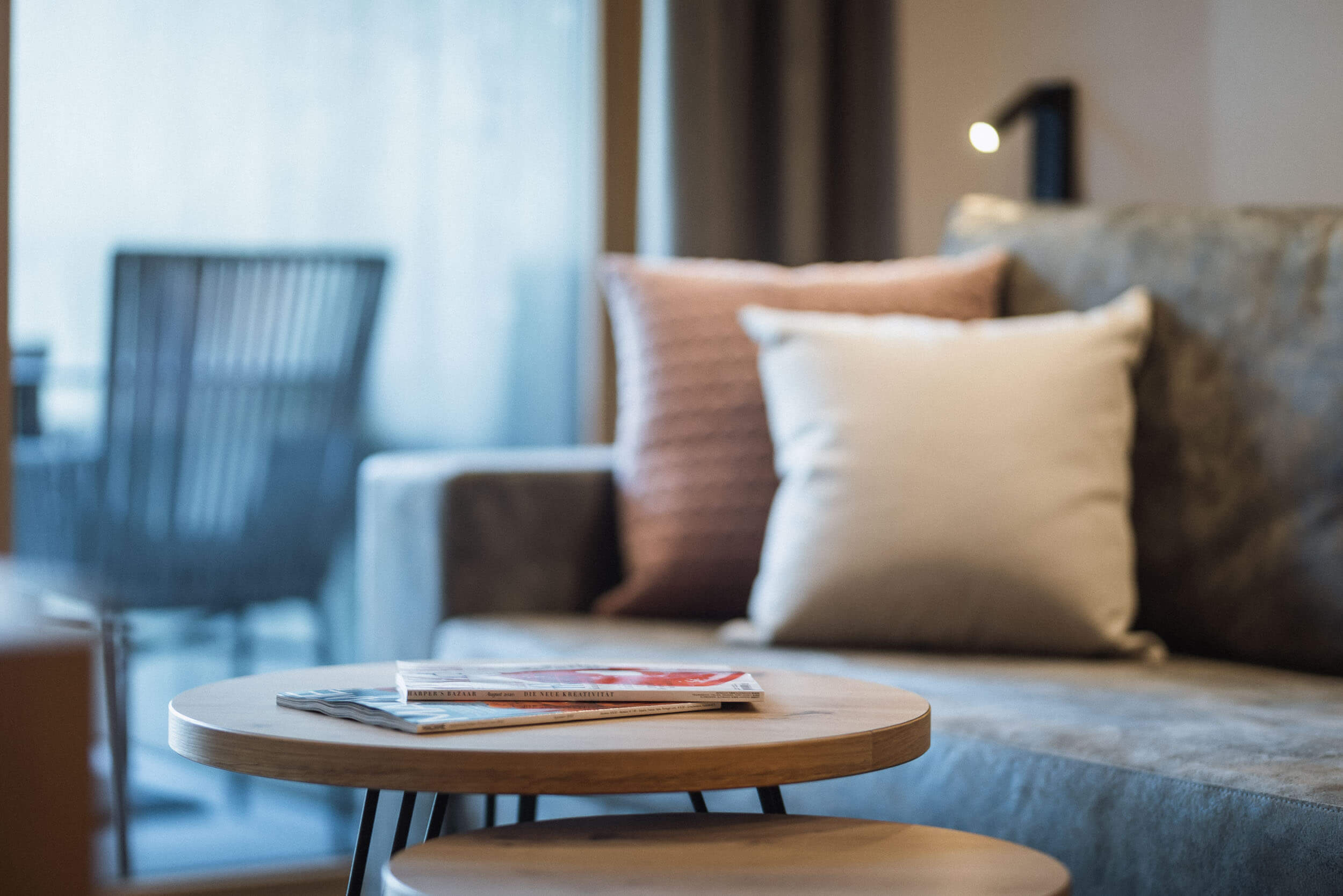 Couchtisch mit Magazine und das Sofa mit 2 Kissen im Hintergrund - AHRIA Apartments