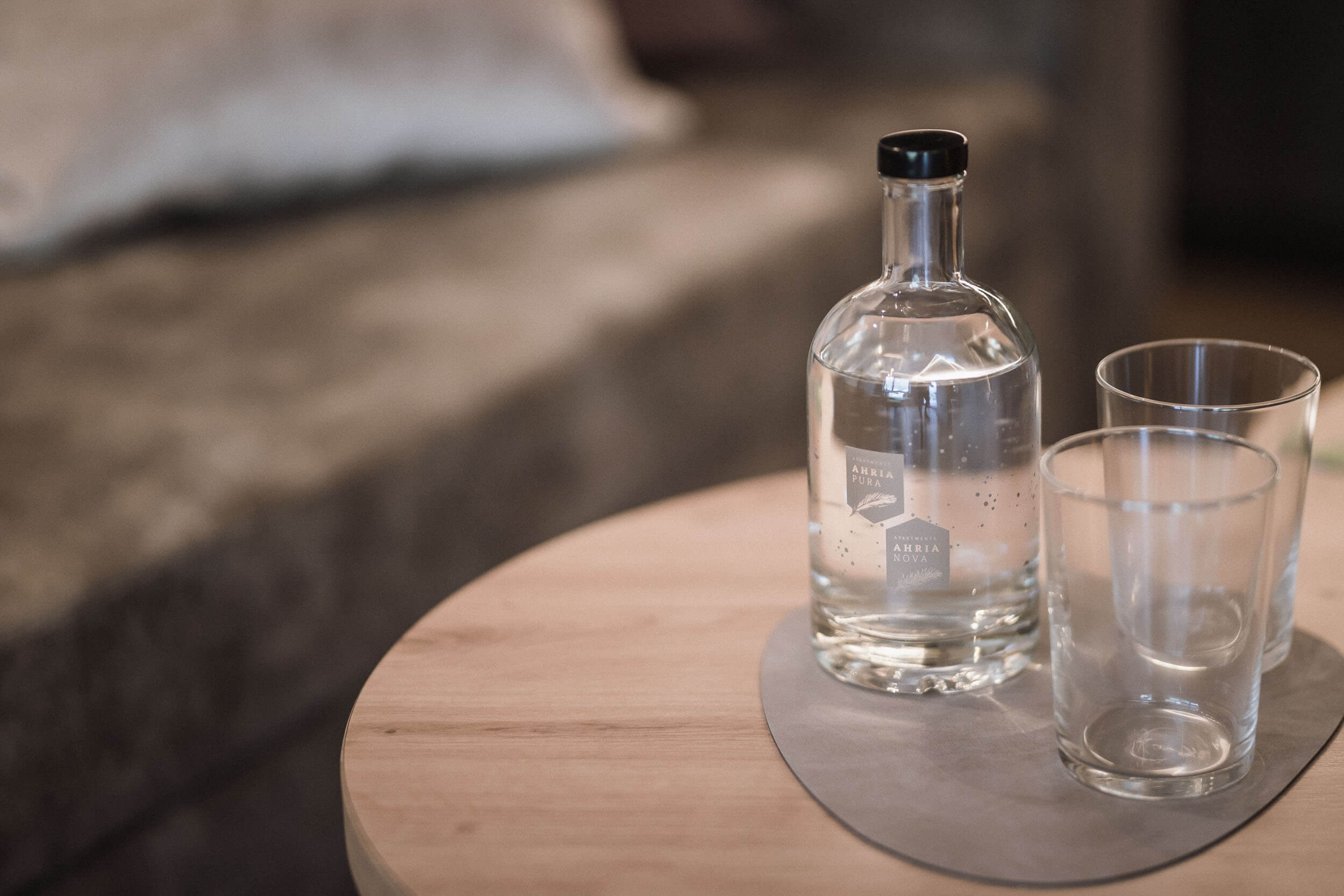 Wasserflasche mit zwei Gläsern im AhriaPura Apartment - AHRIA Apartments