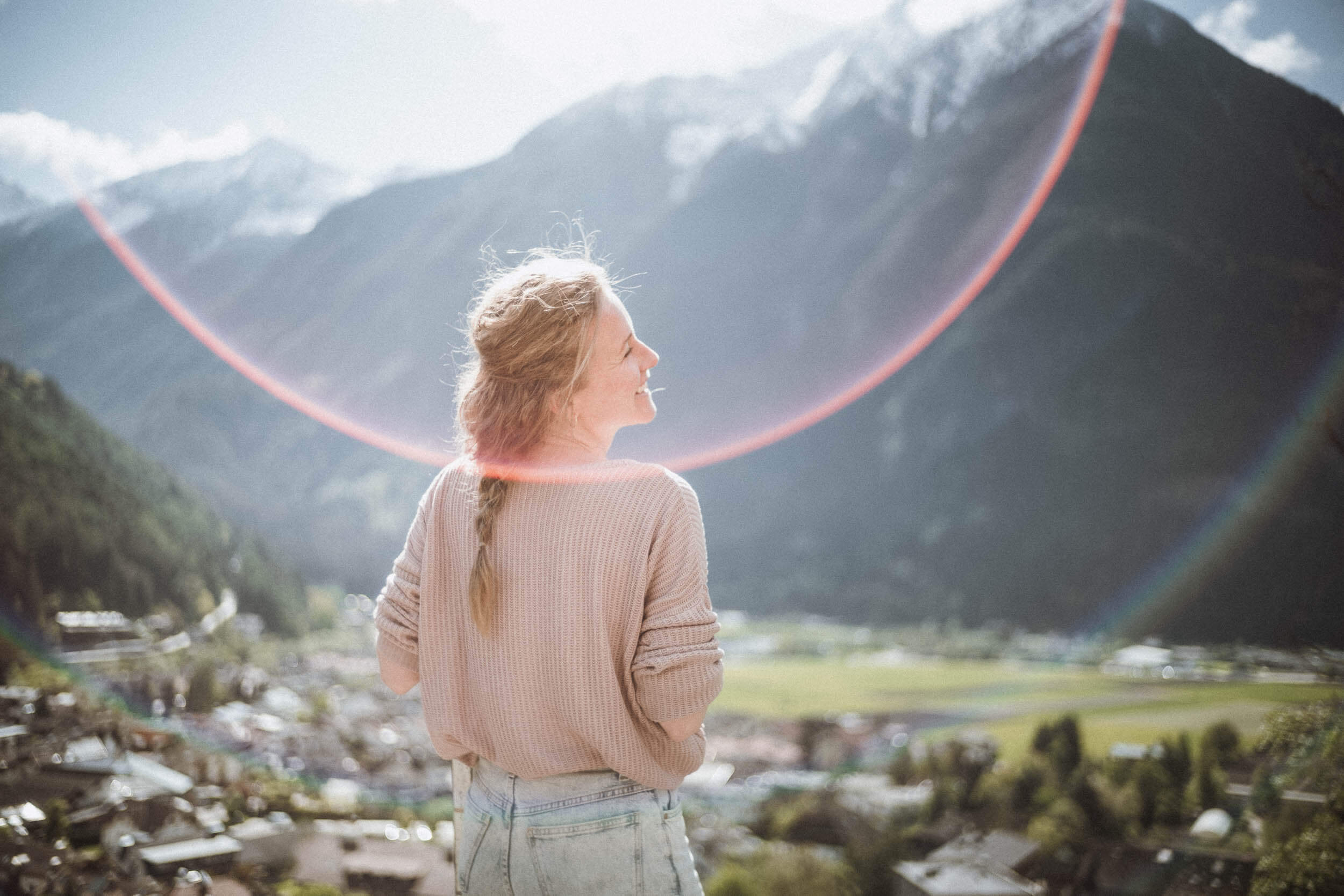 Frau blickt in das sonnige Tal und freut sich - AHRIA Apartments