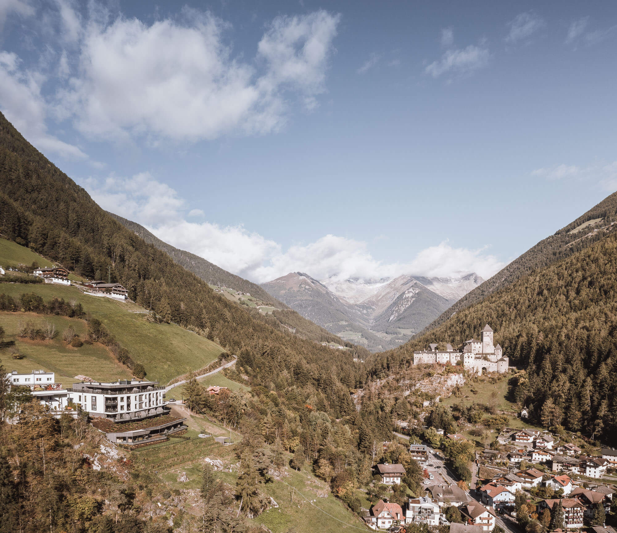 Drohnenaufnahme vom Apartment AhriaPura, Sand in Taufers darunter und das Schloss Taufers im Hintergrund - AHRIA Apartments