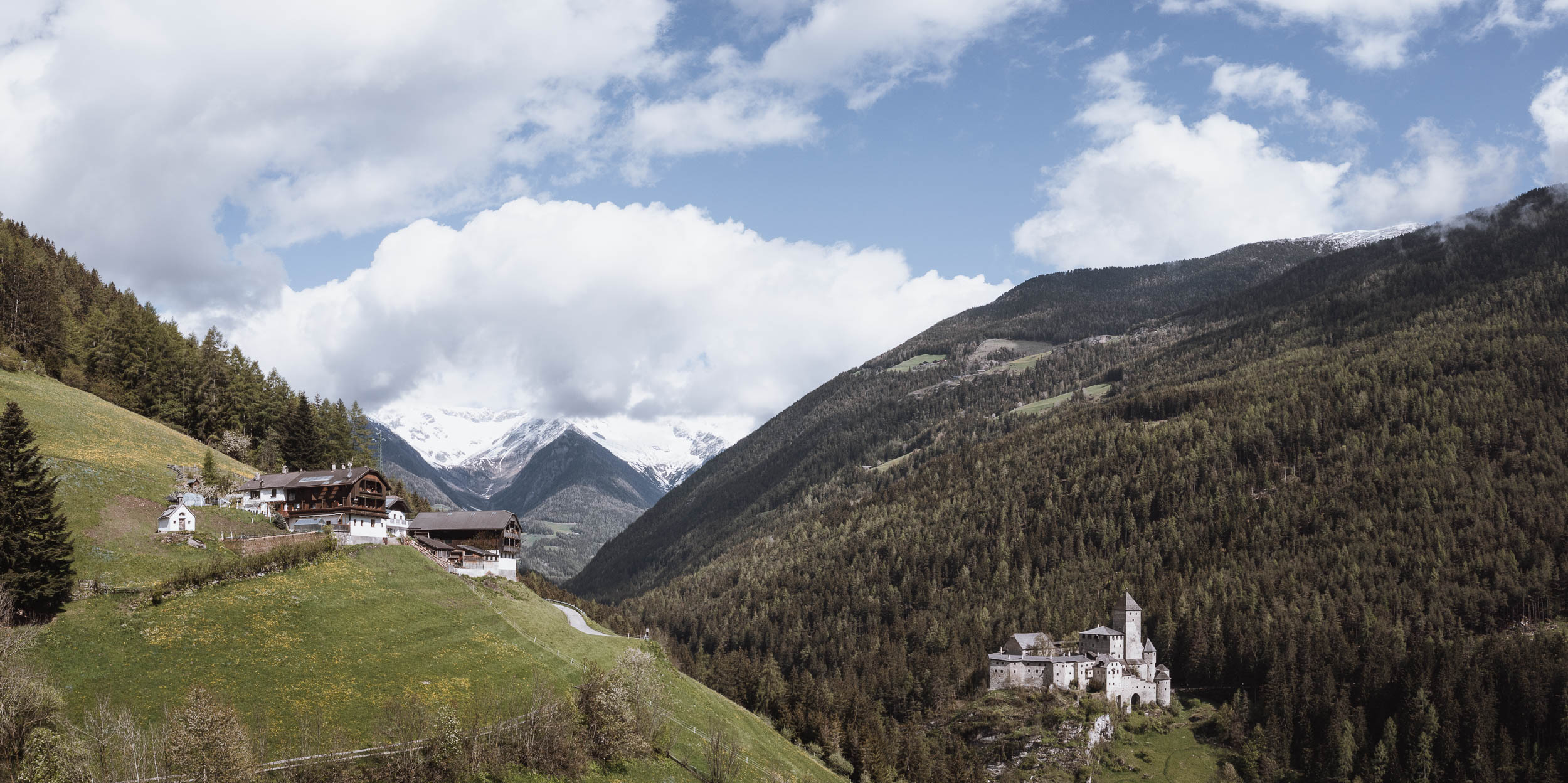 Blick auf einen Berghof und Schloss Taufers im Sommer - AHRIA Apartments