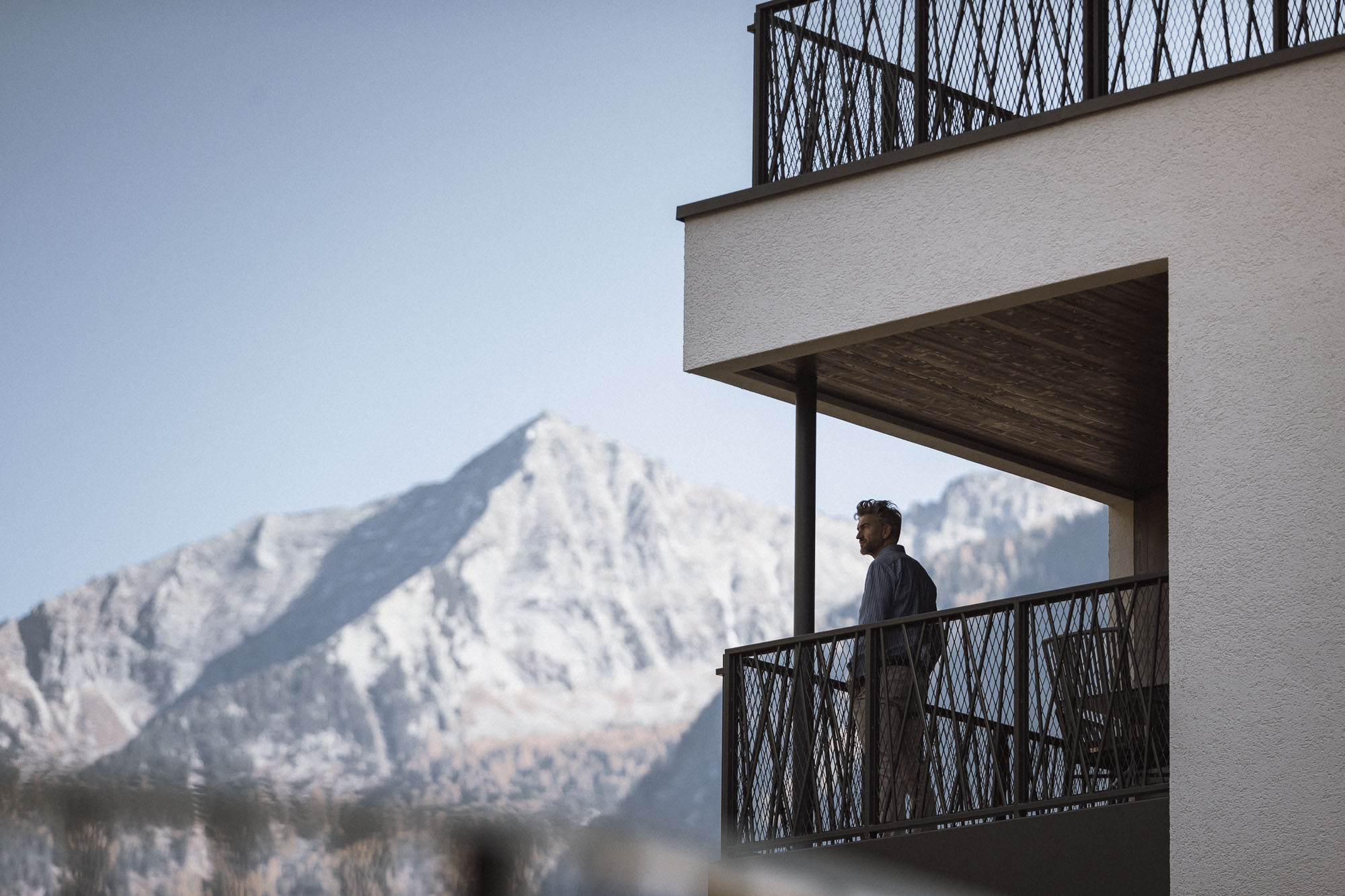 Mann steht auf dem Balkon und blickt in die Ahrntaler Berge - AHRIA Apartments