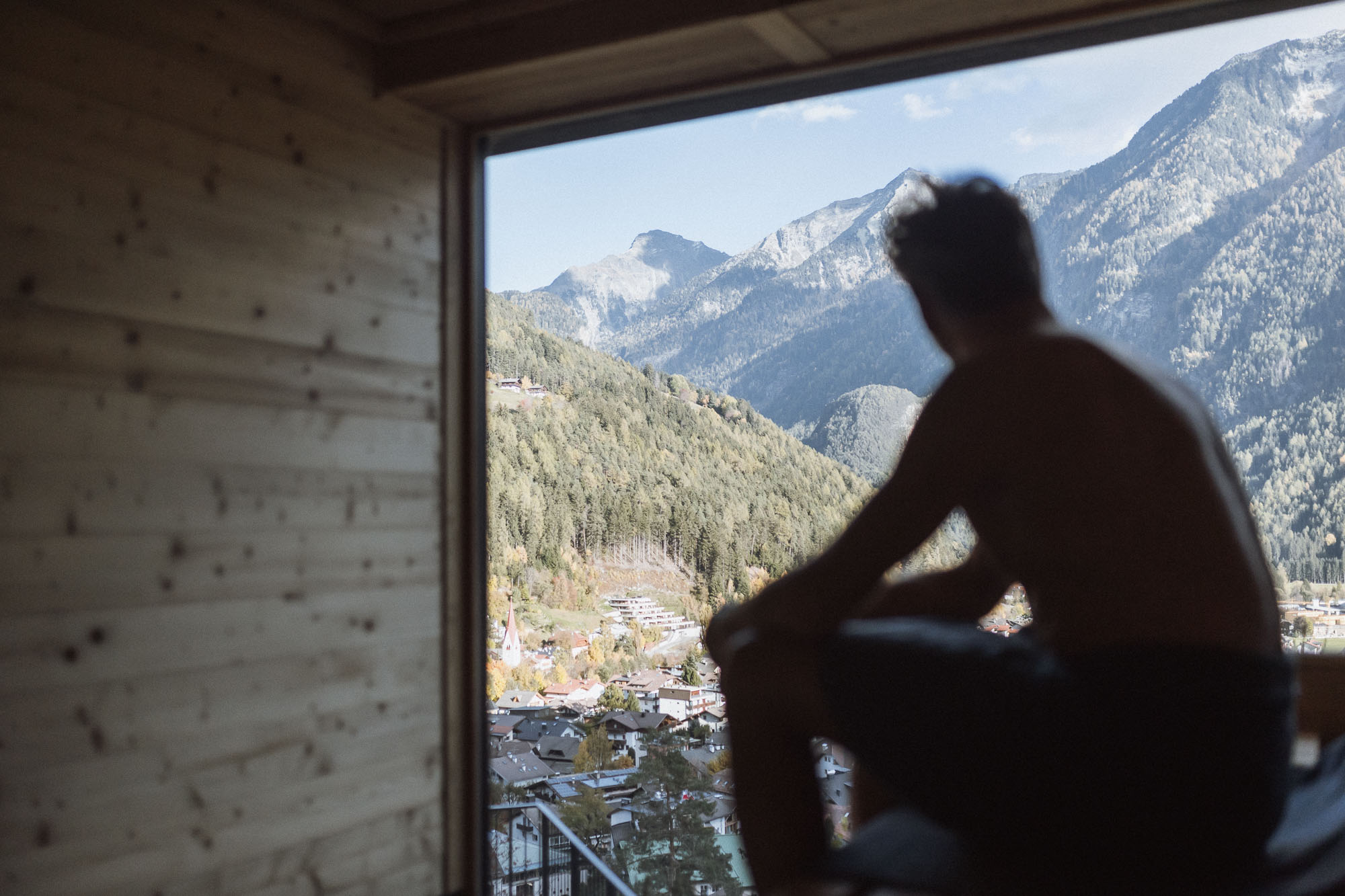 Mann sauniert im Apartment AhriaPura und blickt auf Sand in Taufers und die Ahrntaler Berge - AHRIA Apartments